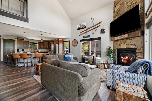 living room featuring a stone fireplace, high vaulted ceiling, and dark hardwood / wood-style flooring