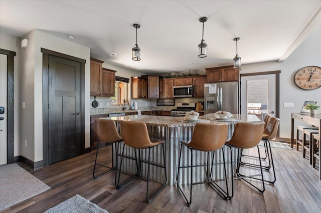 kitchen with a kitchen island, a healthy amount of sunlight, dark hardwood / wood-style floors, and appliances with stainless steel finishes