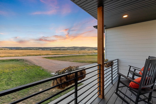 balcony at dusk featuring a rural view