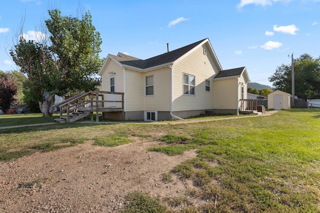 view of side of property featuring a storage shed, a lawn, and a wooden deck