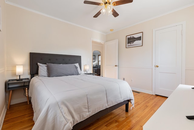 bedroom with light wood-type flooring, ceiling fan, and crown molding