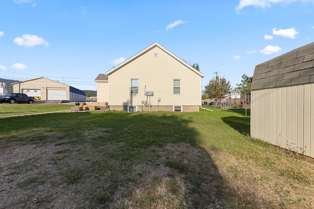 rear view of property with an outdoor structure, a lawn, and a garage