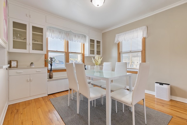 dining room with crown molding and light hardwood / wood-style flooring