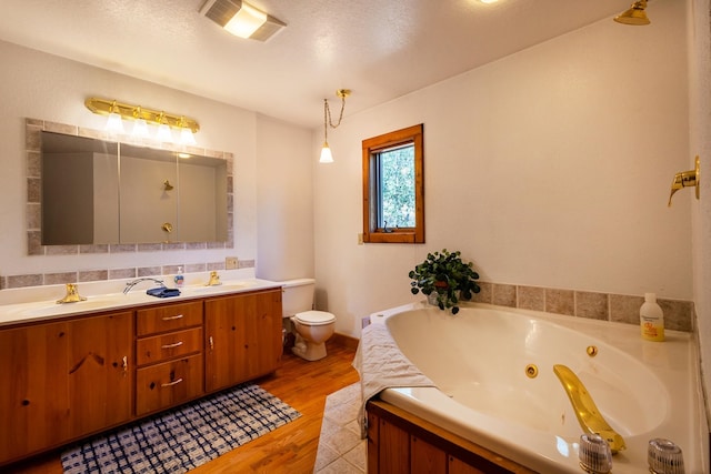 bathroom featuring vanity, a bathtub, wood-type flooring, a textured ceiling, and toilet