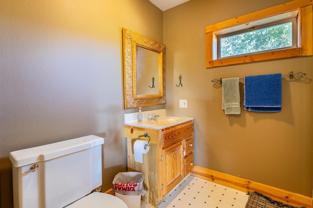 half bathroom with tile patterned floors, vanity, baseboards, and toilet