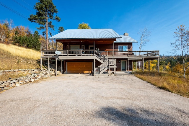 view of front of house featuring a chimney, stairway, driveway, an attached garage, and metal roof
