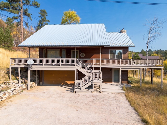 view of front of home featuring a chimney, stone siding, stairs, a garage, and metal roof
