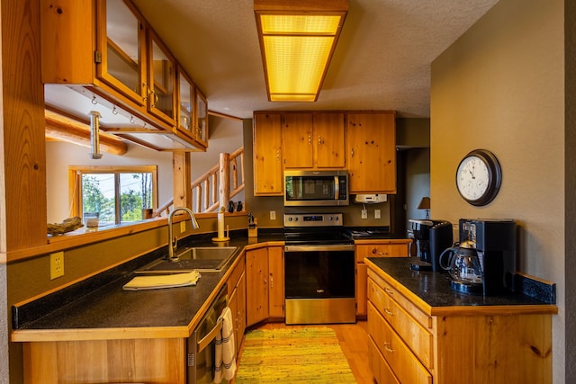 kitchen featuring a textured ceiling, stainless steel appliances, sink, and kitchen peninsula