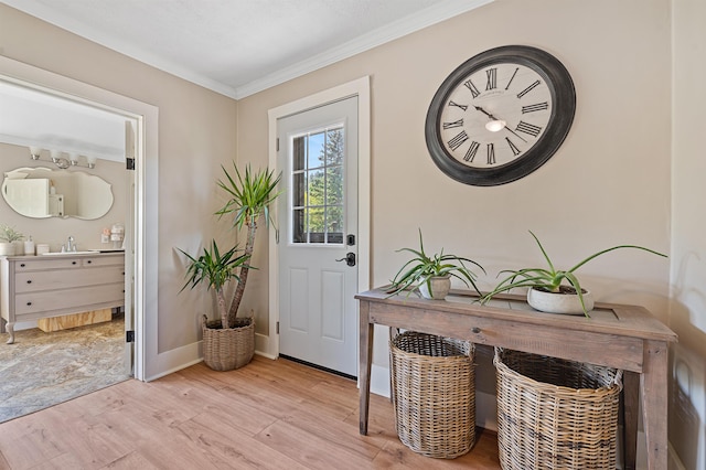 entryway with light wood-type flooring, ornamental molding, and sink