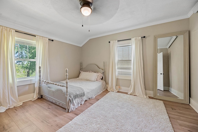 bedroom with light wood-type flooring, ceiling fan, a textured ceiling, and vaulted ceiling