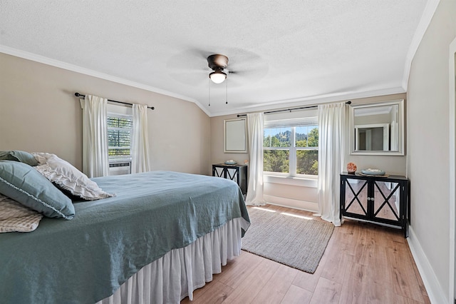 bedroom with ceiling fan, ornamental molding, light wood-type flooring, and multiple windows