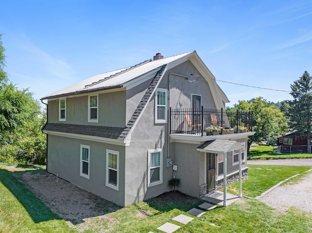 back of property with a balcony and a yard