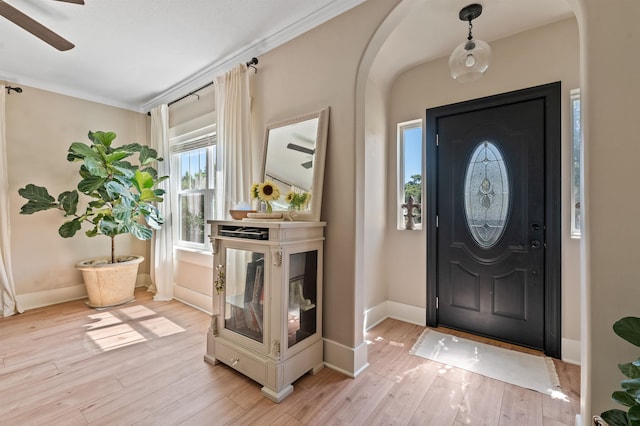 foyer entrance with ceiling fan, ornamental molding, and light hardwood / wood-style flooring