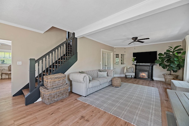 living room featuring a textured ceiling, ceiling fan, ornamental molding, and light wood-type flooring