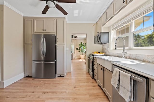 kitchen with light hardwood / wood-style flooring, appliances with stainless steel finishes, sink, ceiling fan, and ornamental molding