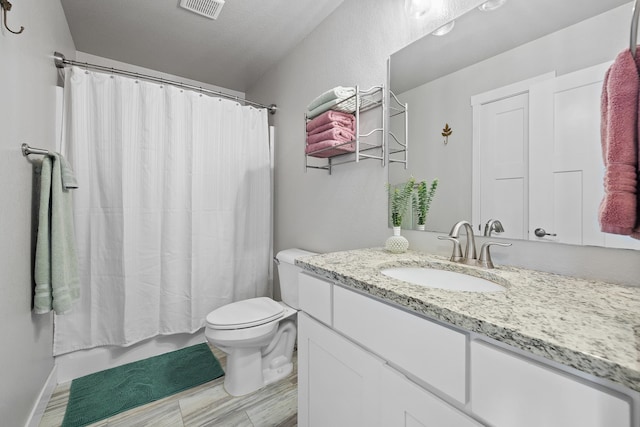 bathroom with a textured ceiling, vanity, toilet, and walk in shower