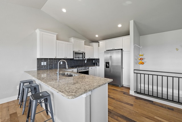 kitchen with white cabinetry, stainless steel appliances, kitchen peninsula, and hardwood / wood-style flooring