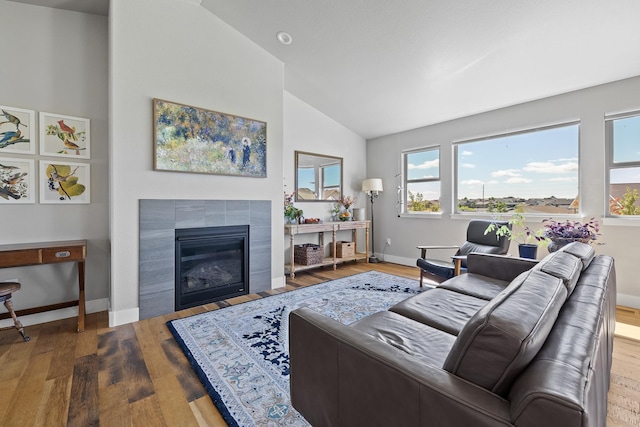 living room with high vaulted ceiling, hardwood / wood-style flooring, and a fireplace