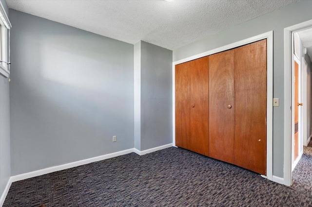 unfurnished bedroom with dark carpet, a closet, and a textured ceiling