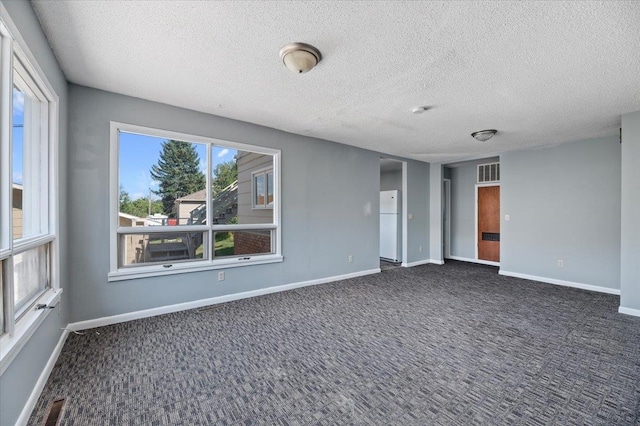 empty room featuring dark colored carpet and a textured ceiling