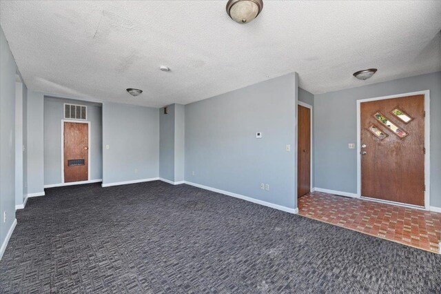 interior space with a textured ceiling and dark colored carpet