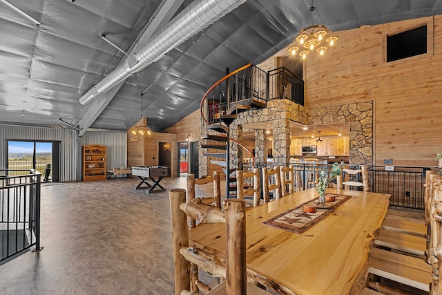 dining room featuring a towering ceiling, concrete floors, and wooden walls