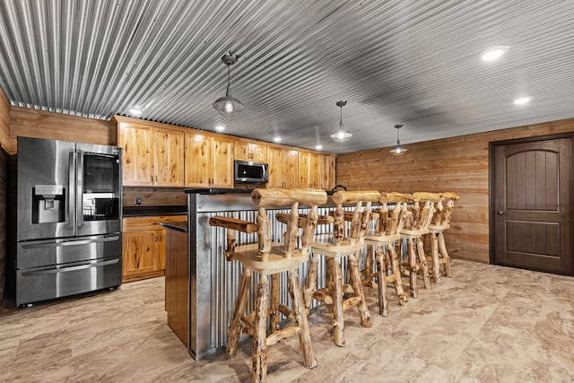 kitchen with hanging light fixtures, stainless steel appliances, and wooden walls