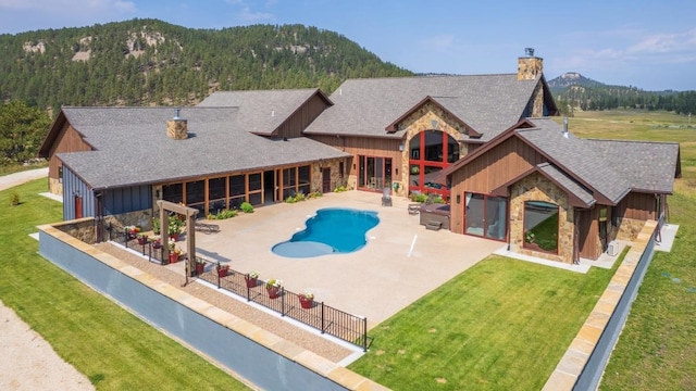 rear view of property featuring a lawn, a patio, and a mountain view