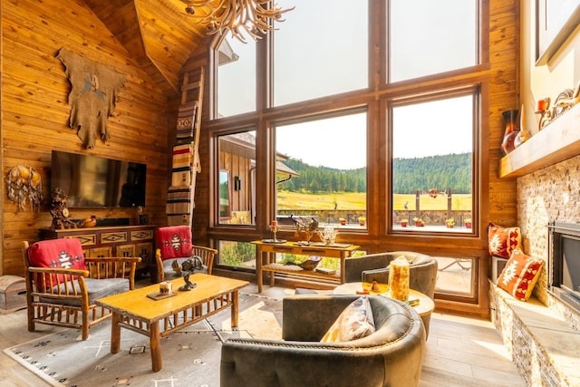 living room with high vaulted ceiling, wooden walls, light hardwood / wood-style flooring, and a wealth of natural light