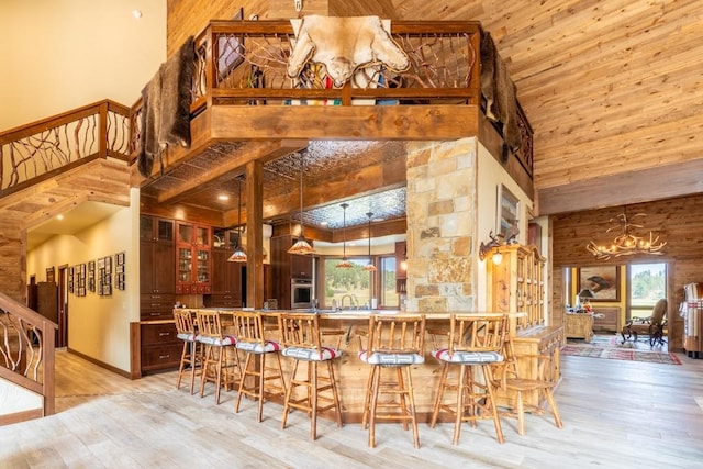 kitchen with stainless steel oven, a chandelier, light hardwood / wood-style floors, and high vaulted ceiling