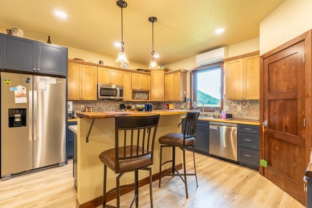 kitchen featuring a breakfast bar, stainless steel appliances, pendant lighting, and light hardwood / wood-style flooring