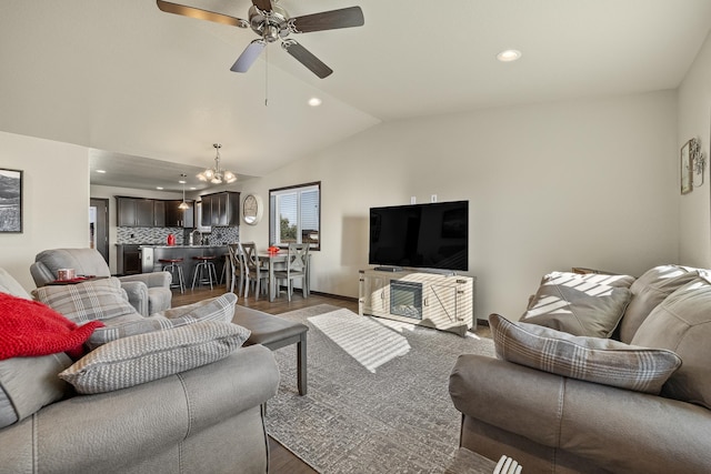 living room with ceiling fan with notable chandelier, vaulted ceiling, and dark wood-type flooring