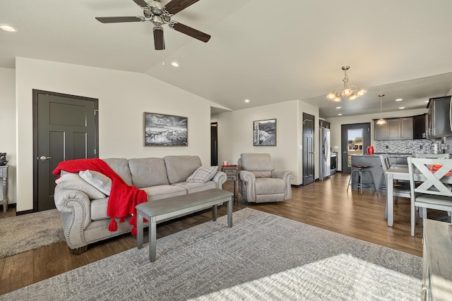 living room with vaulted ceiling, sink, ceiling fan with notable chandelier, and dark wood-type flooring