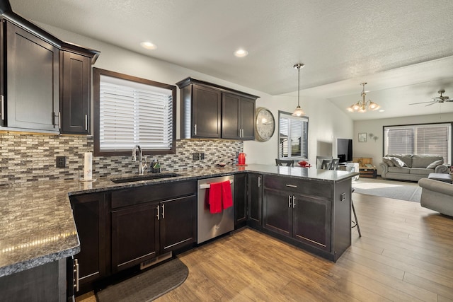 kitchen with light hardwood / wood-style floors, kitchen peninsula, dishwasher, decorative light fixtures, and sink