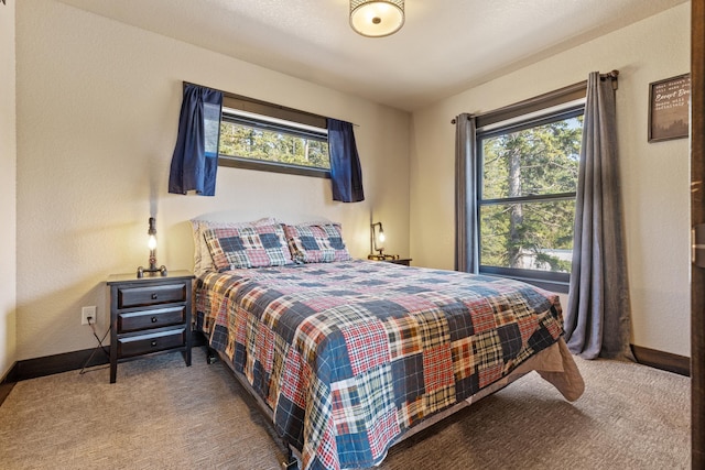 carpeted bedroom with multiple windows, a textured wall, and baseboards