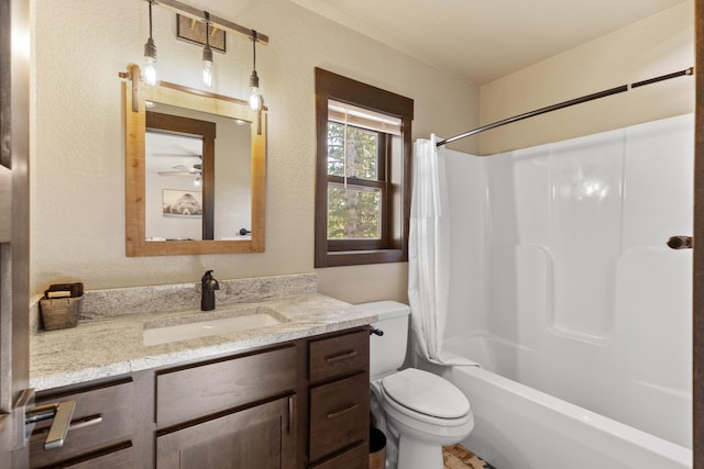 bathroom featuring vanity, toilet, a textured wall, and shower / bath combo
