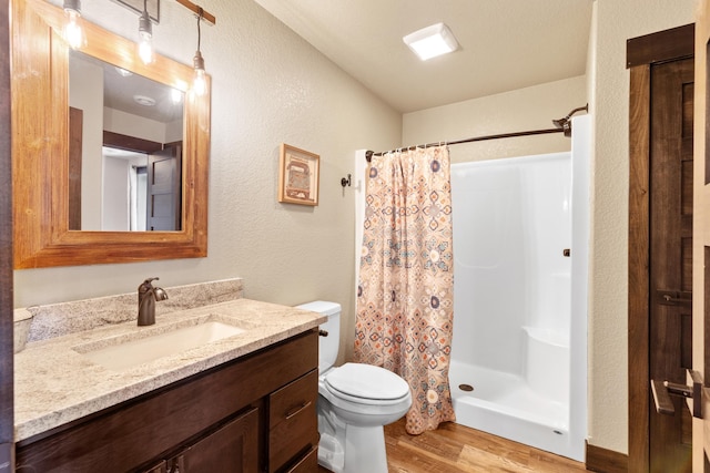 full bath featuring wood finished floors, toilet, a stall shower, and vanity