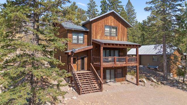 back of property with metal roof, board and batten siding, a wooden deck, and stairway