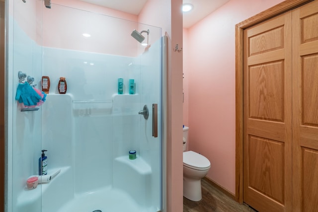 bathroom with walk in shower, toilet, and hardwood / wood-style flooring