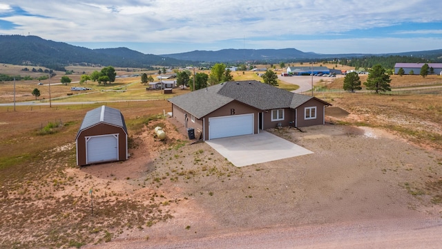 ranch-style house featuring central AC unit, a garage, a rural view, and a mountain view