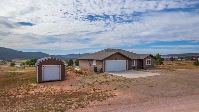 ranch-style home with a storage unit, a mountain view, and a garage