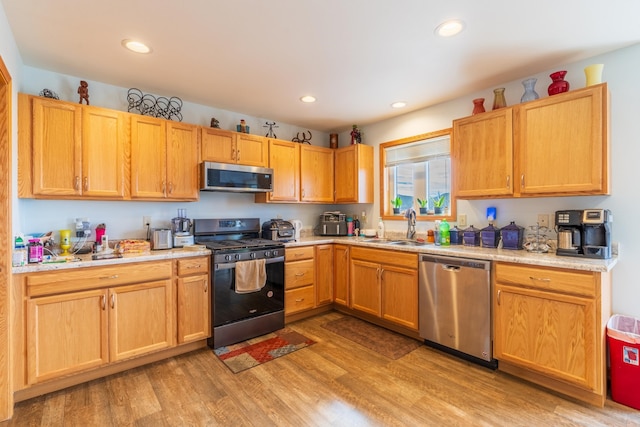 kitchen with stainless steel appliances, sink, and light hardwood / wood-style flooring