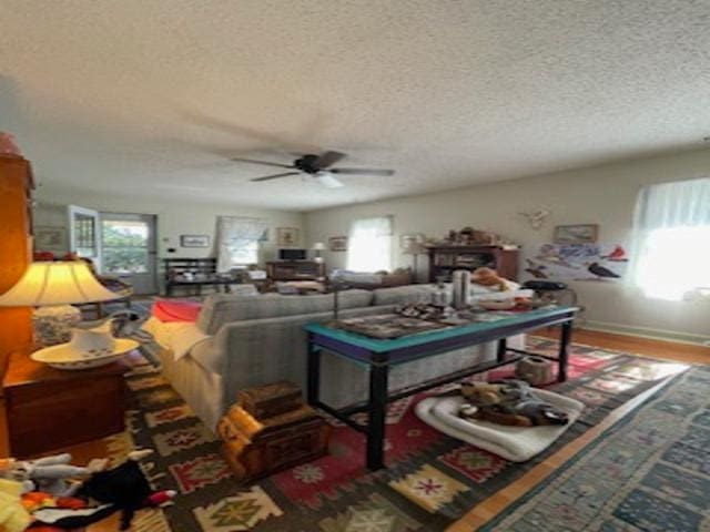 living room with ceiling fan, plenty of natural light, and a textured ceiling