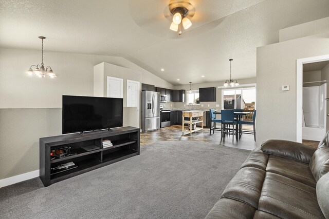 carpeted living room featuring ceiling fan with notable chandelier, vaulted ceiling, a textured ceiling, and sink