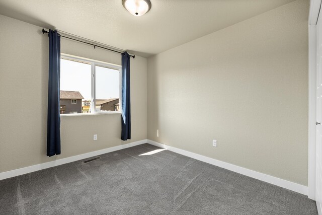 unfurnished room with dark colored carpet