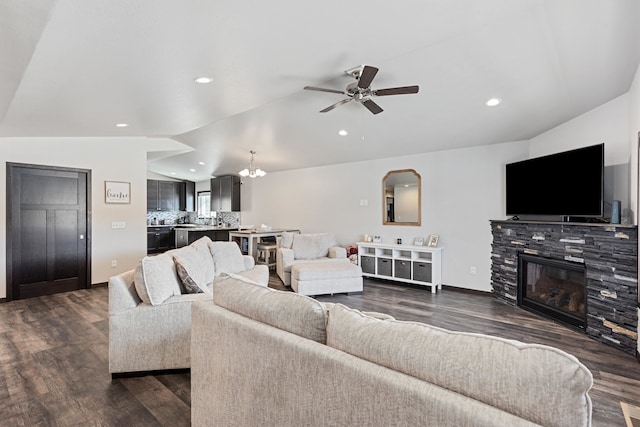 living room with ceiling fan with notable chandelier, lofted ceiling, dark hardwood / wood-style floors, and a fireplace