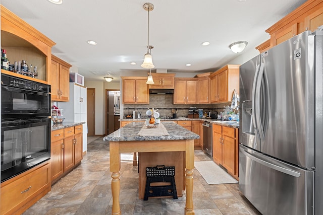 kitchen with light stone counters, hanging light fixtures, tasteful backsplash, appliances with stainless steel finishes, and a center island