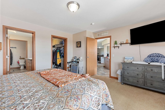 carpeted bedroom featuring ensuite bath, a closet, and a walk in closet