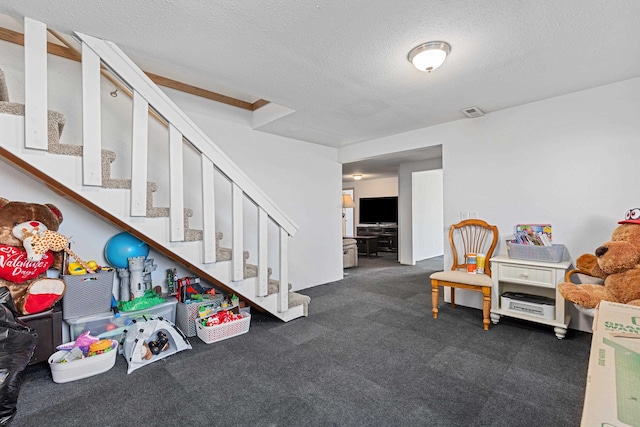 rec room with dark carpet and a textured ceiling