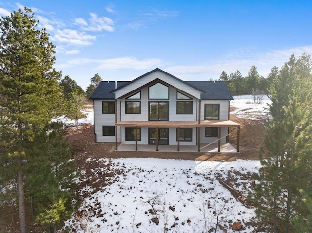 snow covered back of property with a patio area